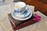 Alice in Wonderland - vintage tea cup candles sits on top of old books and bespoke table runner